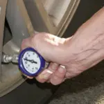 hand using gauge to check auto tire air pressure