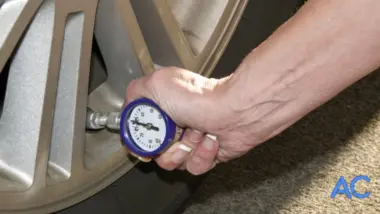 hand using gauge to check auto tire air pressure